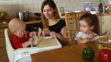 一家人在阳光明媚的白色厨房里吃早餐。 年轻的母亲喂养两个孩子。 <strong>儿童健康</strong>营养